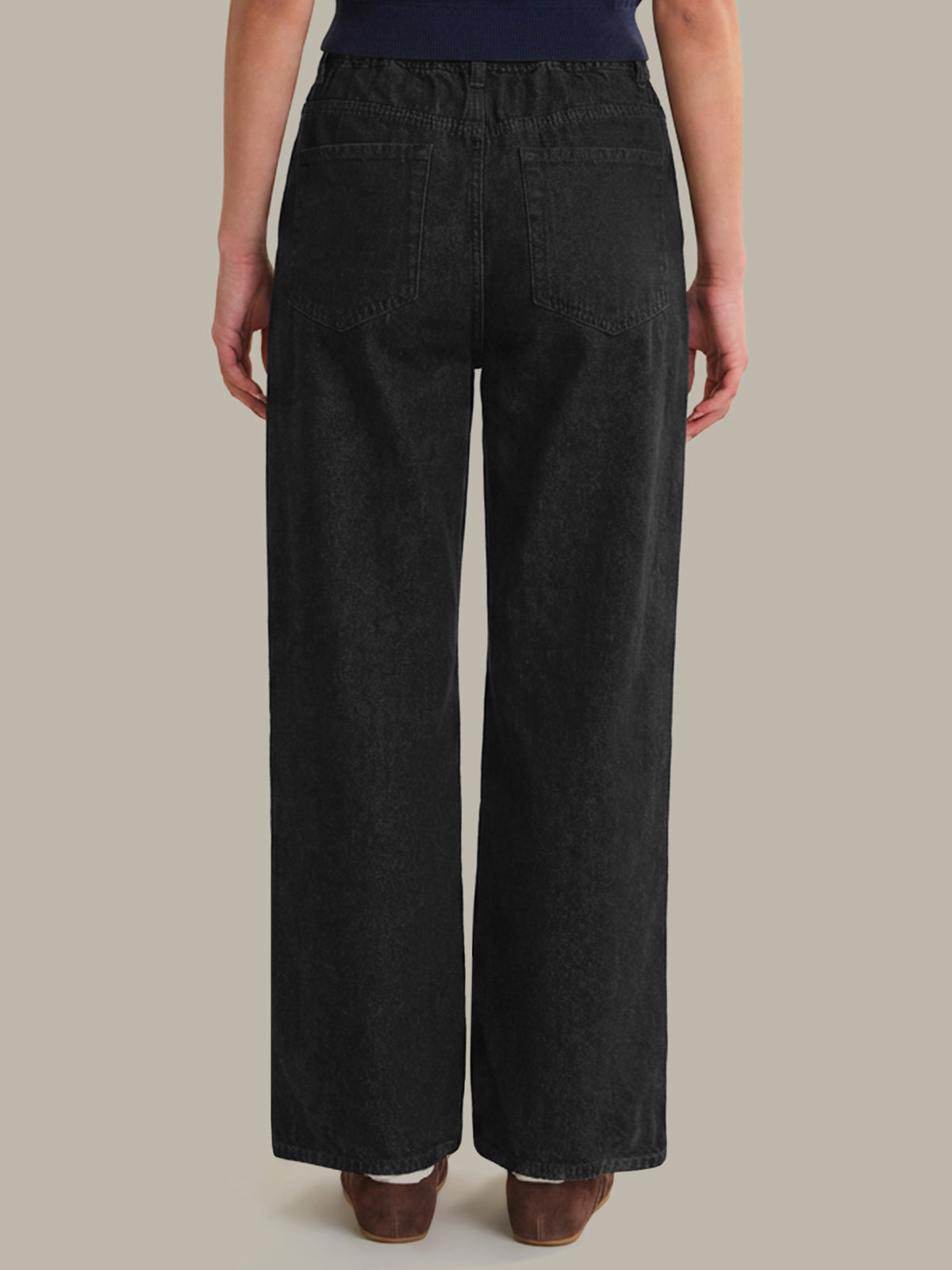 Person wearing black wide-leg pants on a neutral background