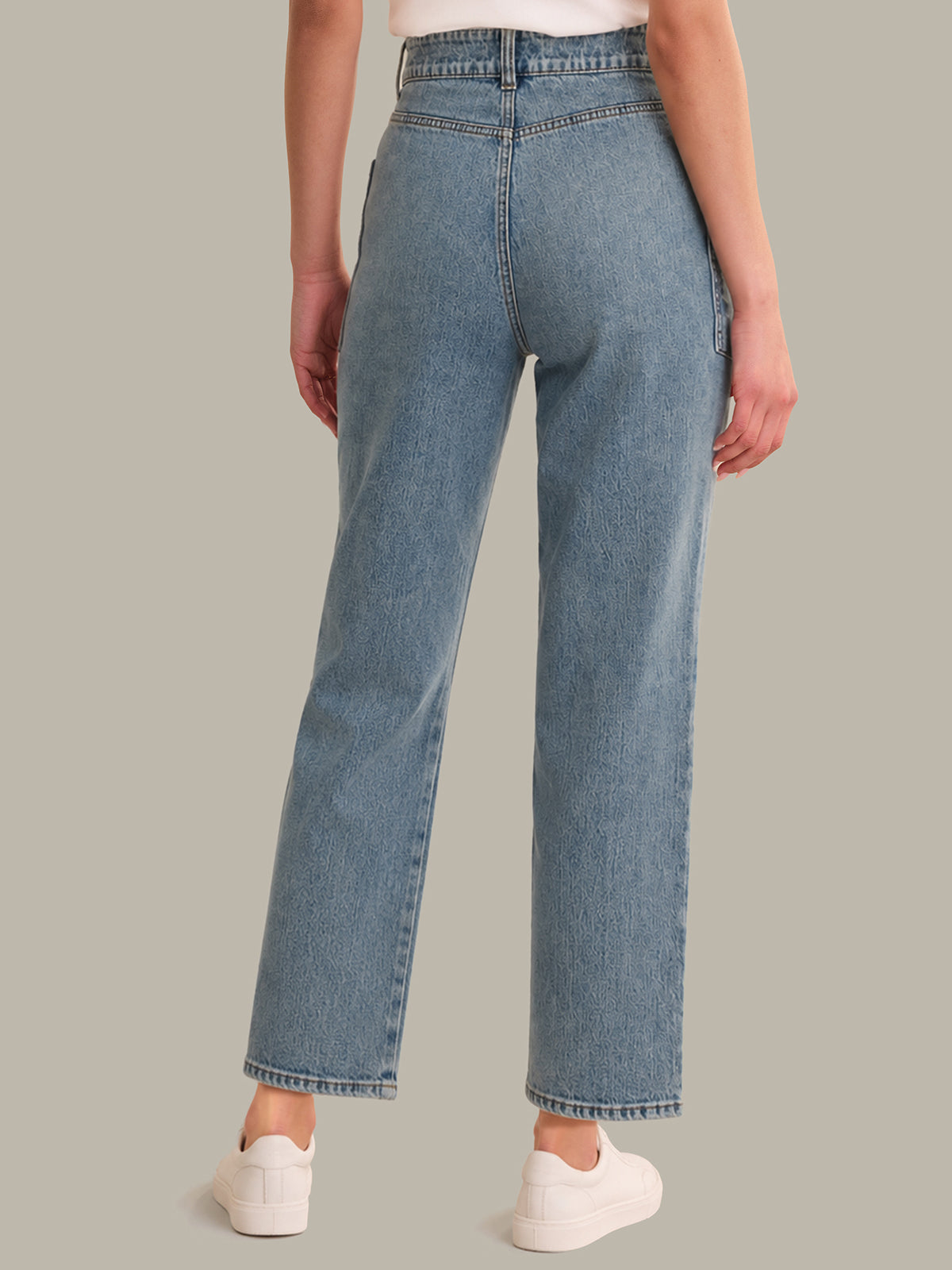 Person wearing light blue jeans on a plain background