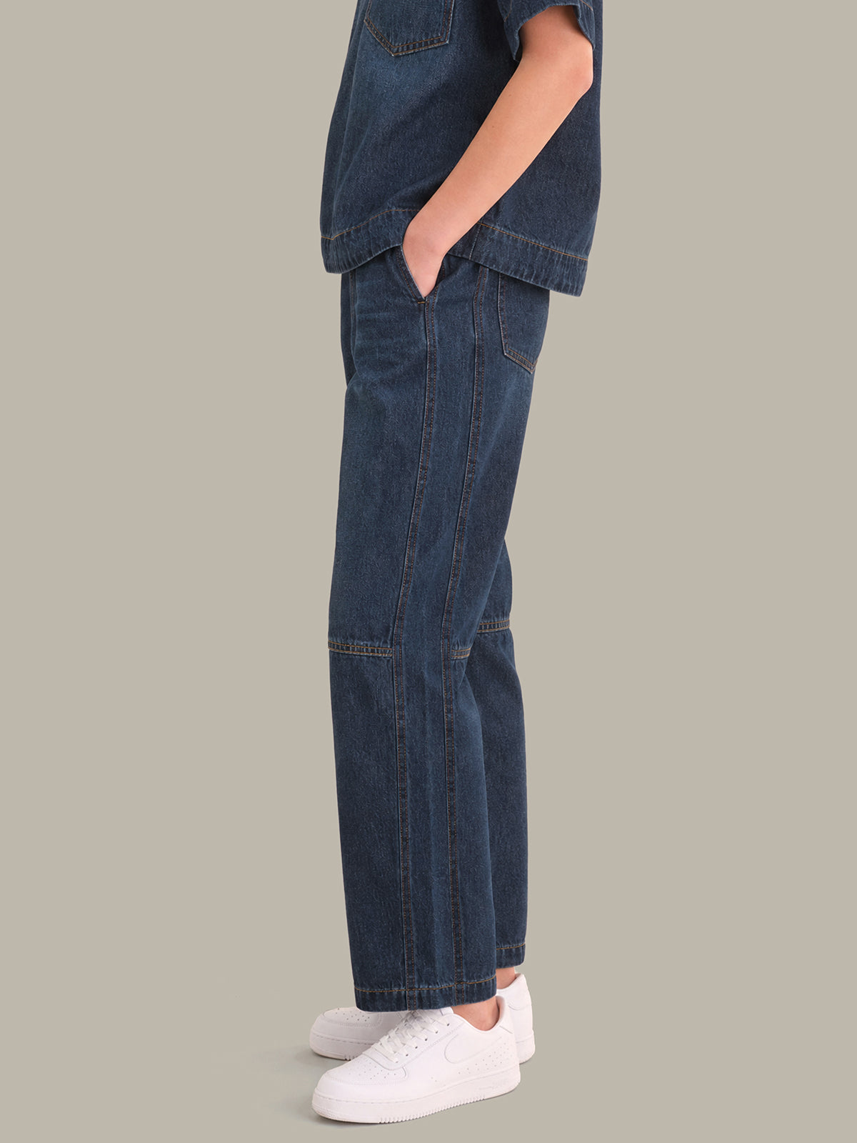 Person wearing blue jeans and white sneakers on a gray background