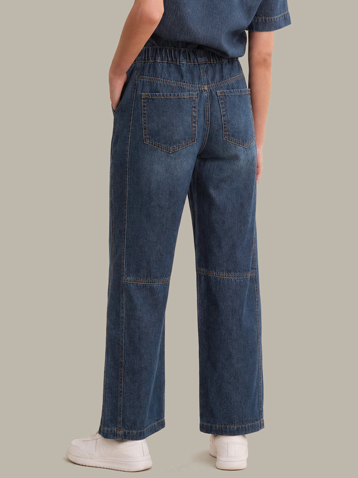 Person wearing blue jeans on a plain background