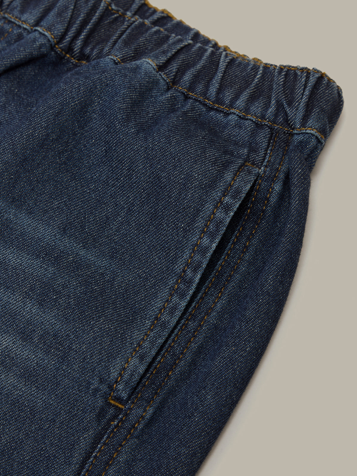 Close-up of blue denim shorts with a beige background