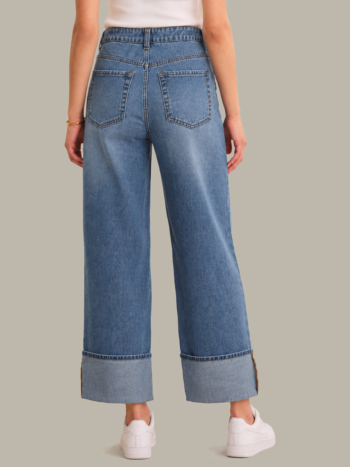 Wide-leg blue jeans worn by a person on a neutral background