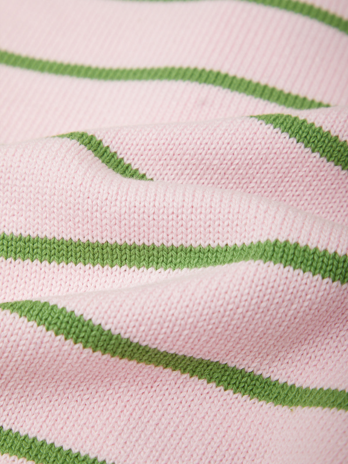 A close-up of a knitted fabric with a light pink base and wavy green stripes.
