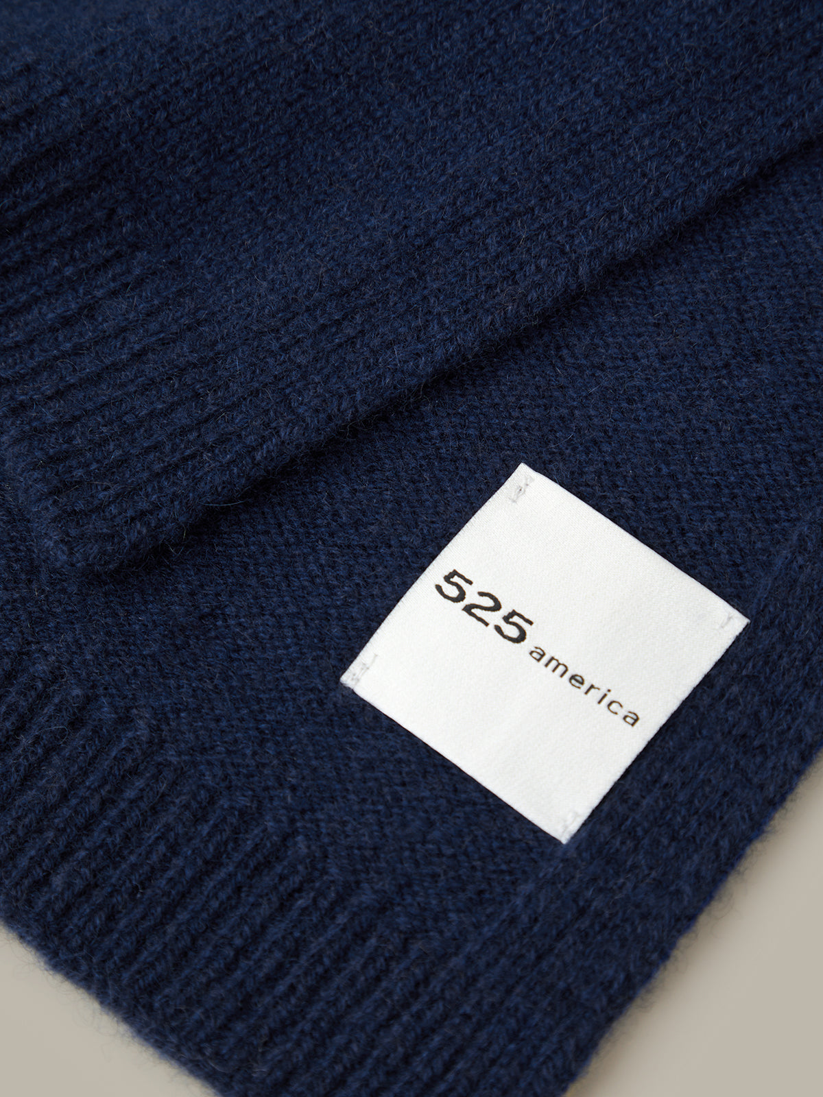 Navy blue knit beanie with a white label displaying '525 america' on a neutral background