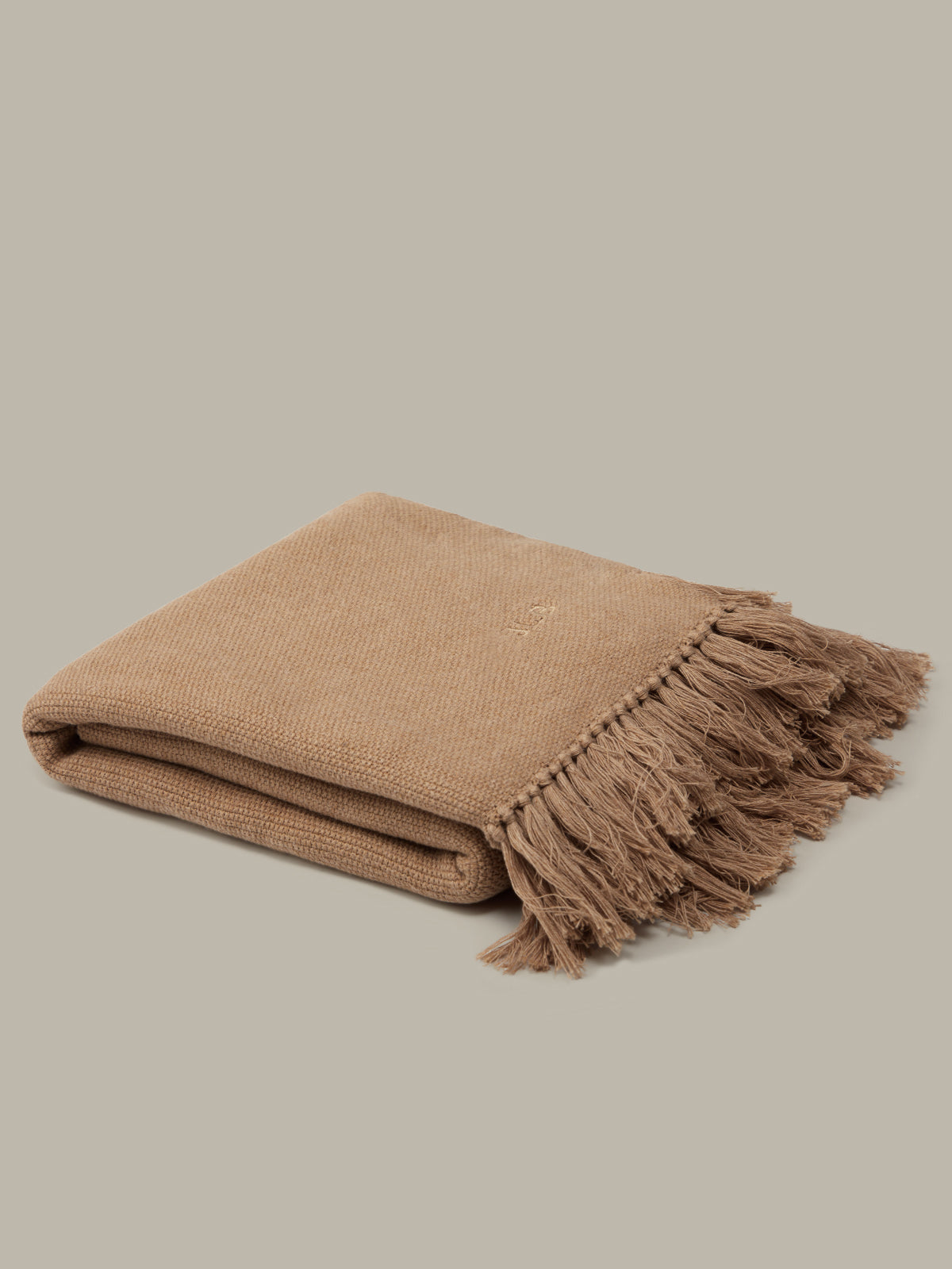 Beige blanket with fringes on a beige background