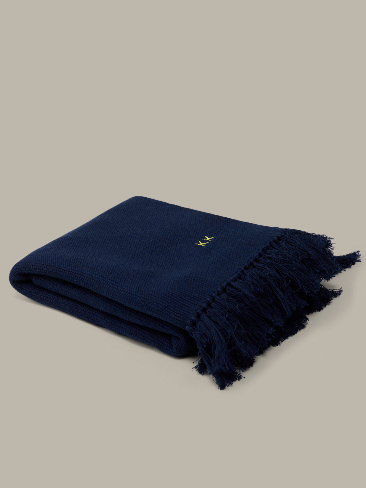 Navy blue blanket with a gold monogram on a beige background