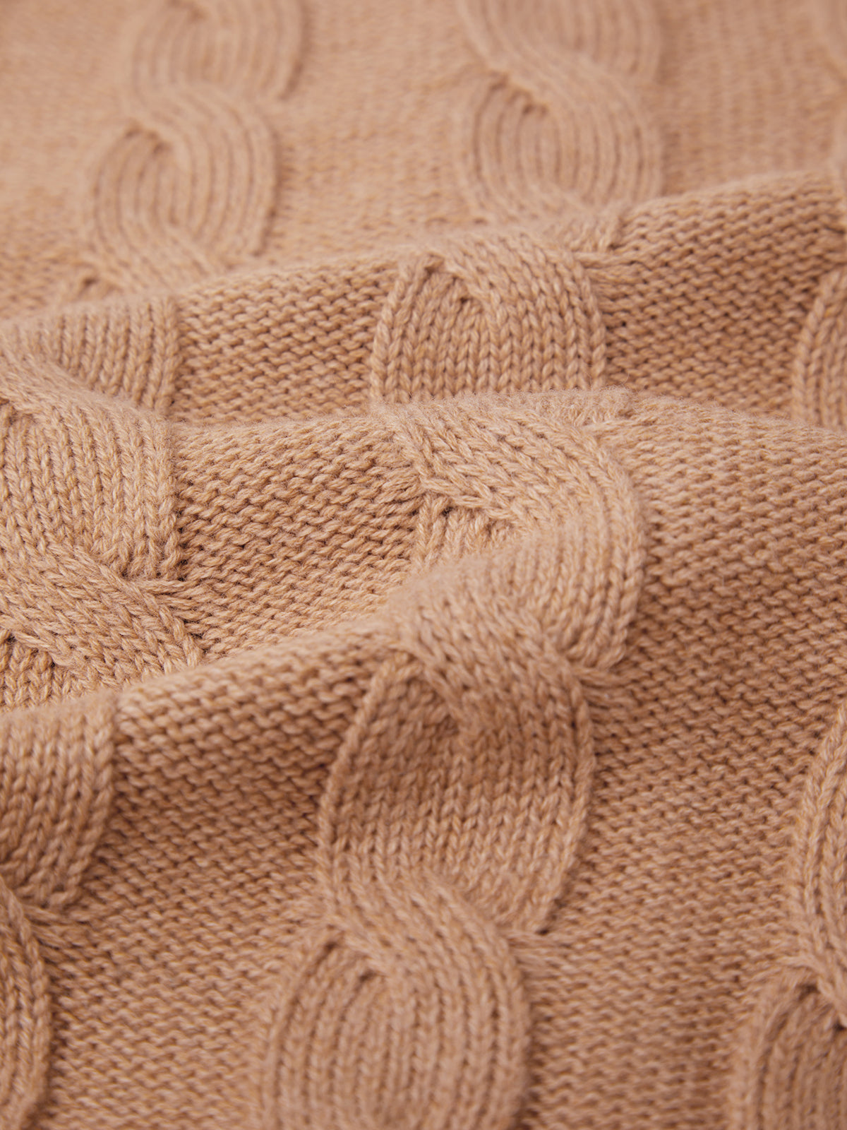Close-up of a beige cable knit fabric from 525 America, reminiscent of a cozy cardigan, showcasing interlocking loops. The texture and weave highlight the detailed craftsmanship, perfect for seasonal colorways.