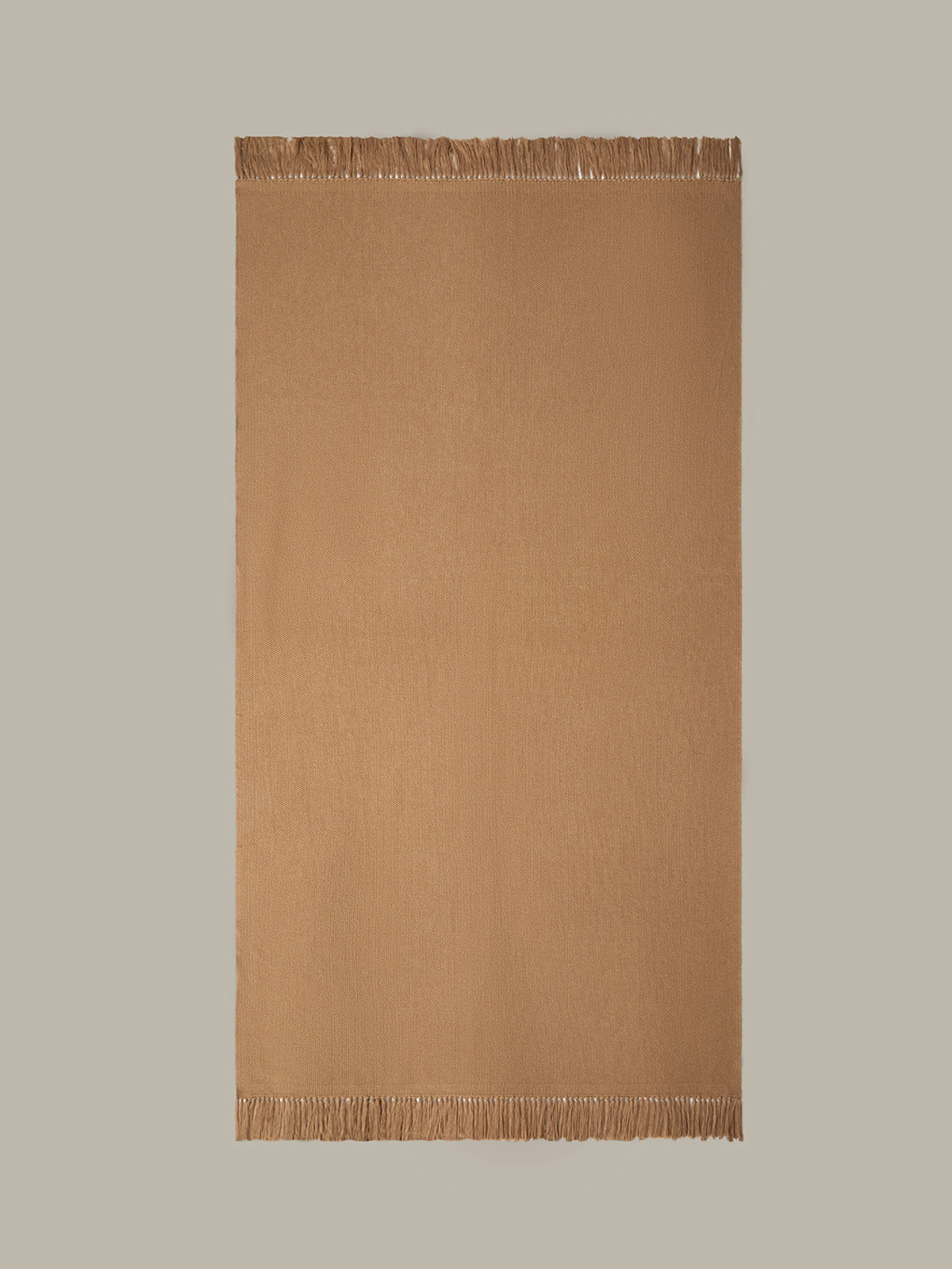 Brown woven blanket with fringes on a beige background
