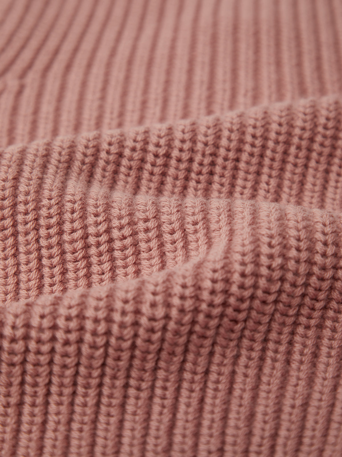 Close-up of a textured, ribbed knit fabric in dusty pink by 525 America, crafted from 100% cotton, showcasing the detailed pattern and fibers for a versatile look.