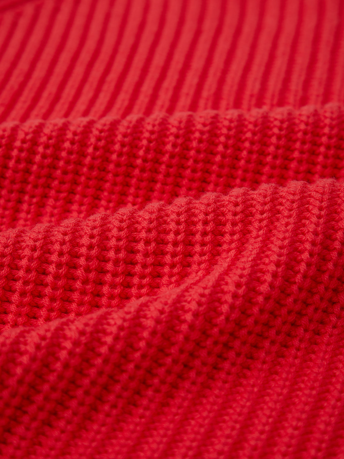 Close-up of a 525 America red cotton shaker stitch sweater with ribbed, textured pattern showing visible rows, horizontal ridges, and detailed stitching that highlight the fabric’s depth and softness.