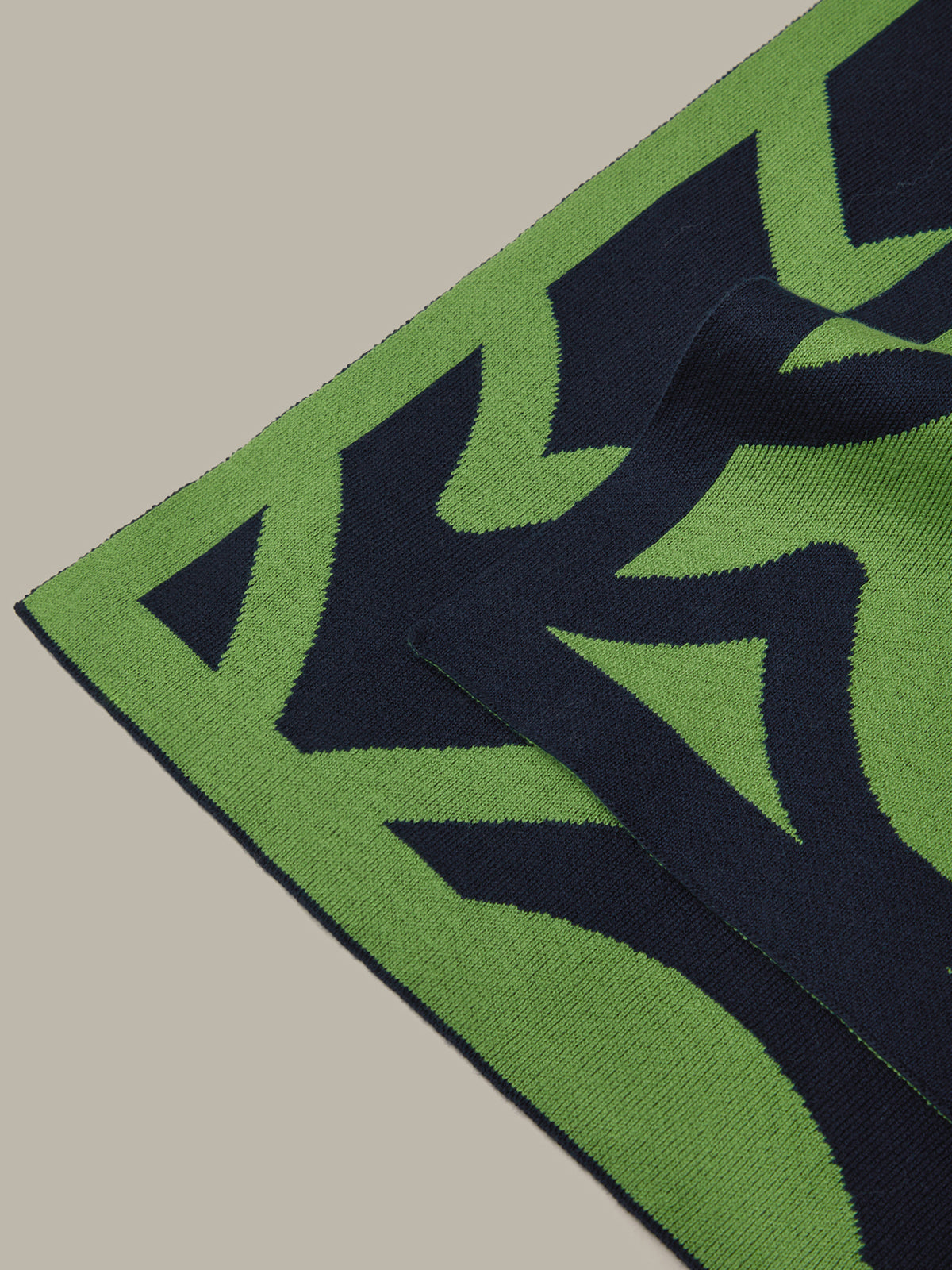 Close-up of a green and black patterned rug on a beige floor.