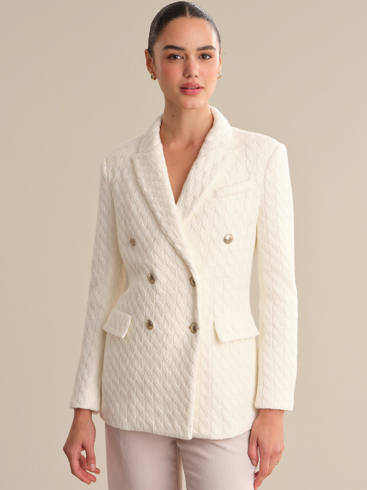 Woman wearing a white quilted blazer against a beige background