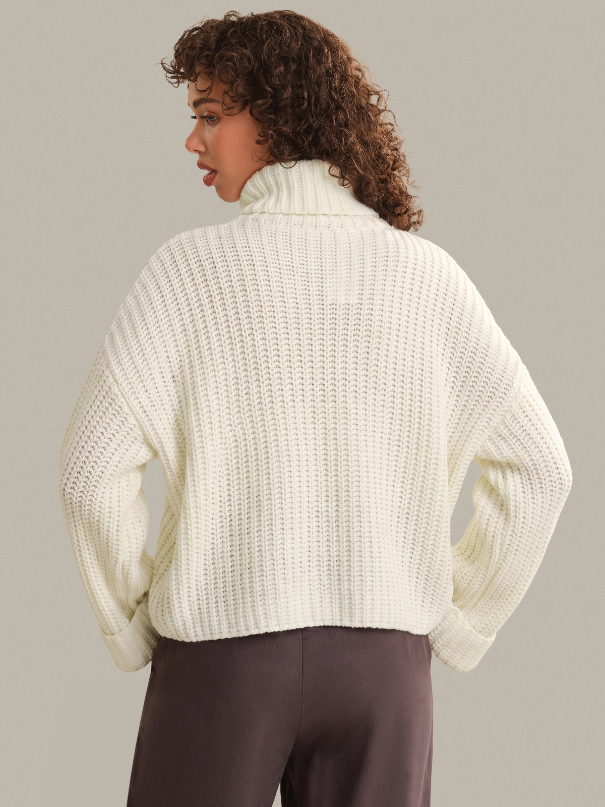 Person wearing a white textured sweater against a neutral background