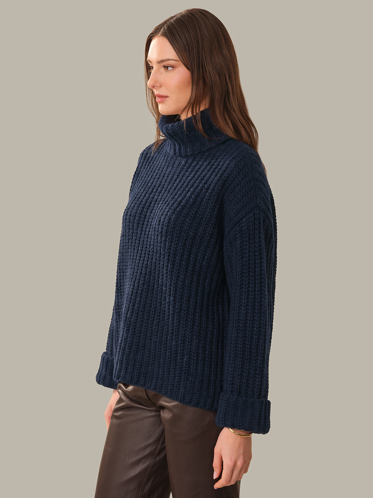 Woman wearing a dark blue ribbed sweater against a neutral background