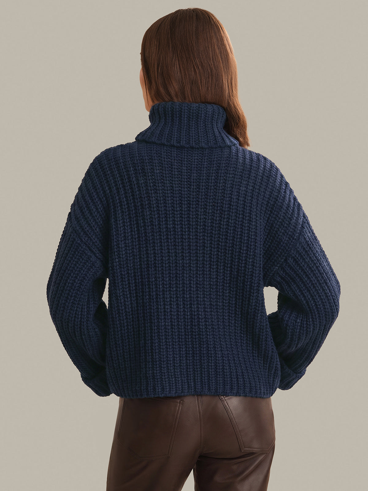 Person wearing a blue ribbed sweater against a neutral background