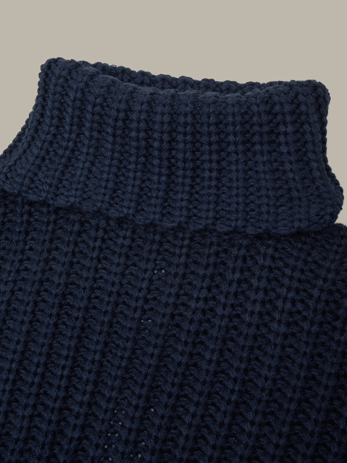 Close-up of a navy blue knitted sweater on a beige background