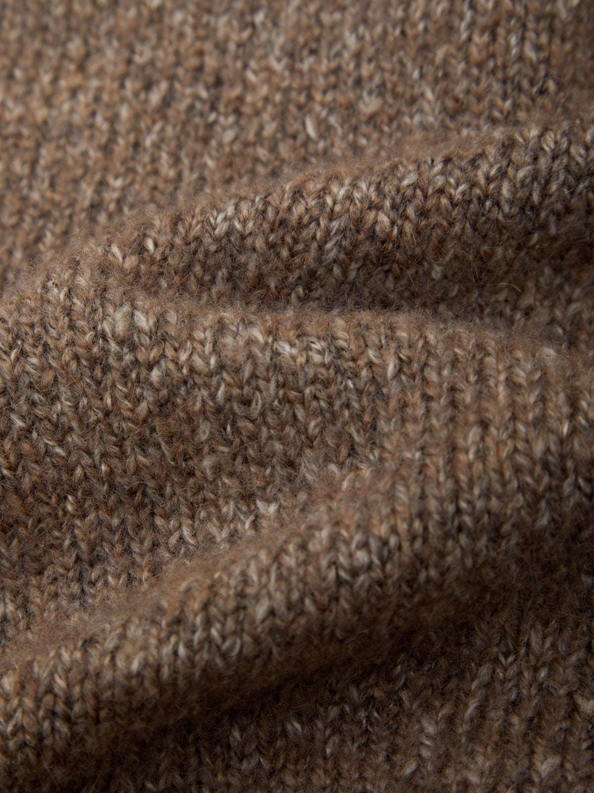 Close-up of a brown and beige heathered knit fabric texture with soft folds.