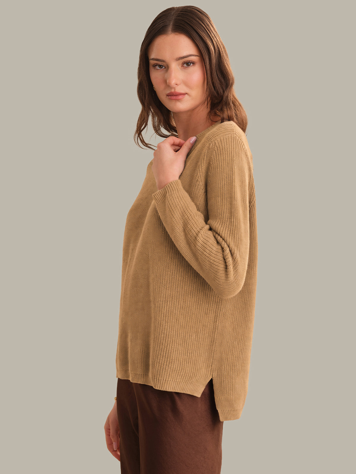 Woman wearing a beige sweater against a plain background