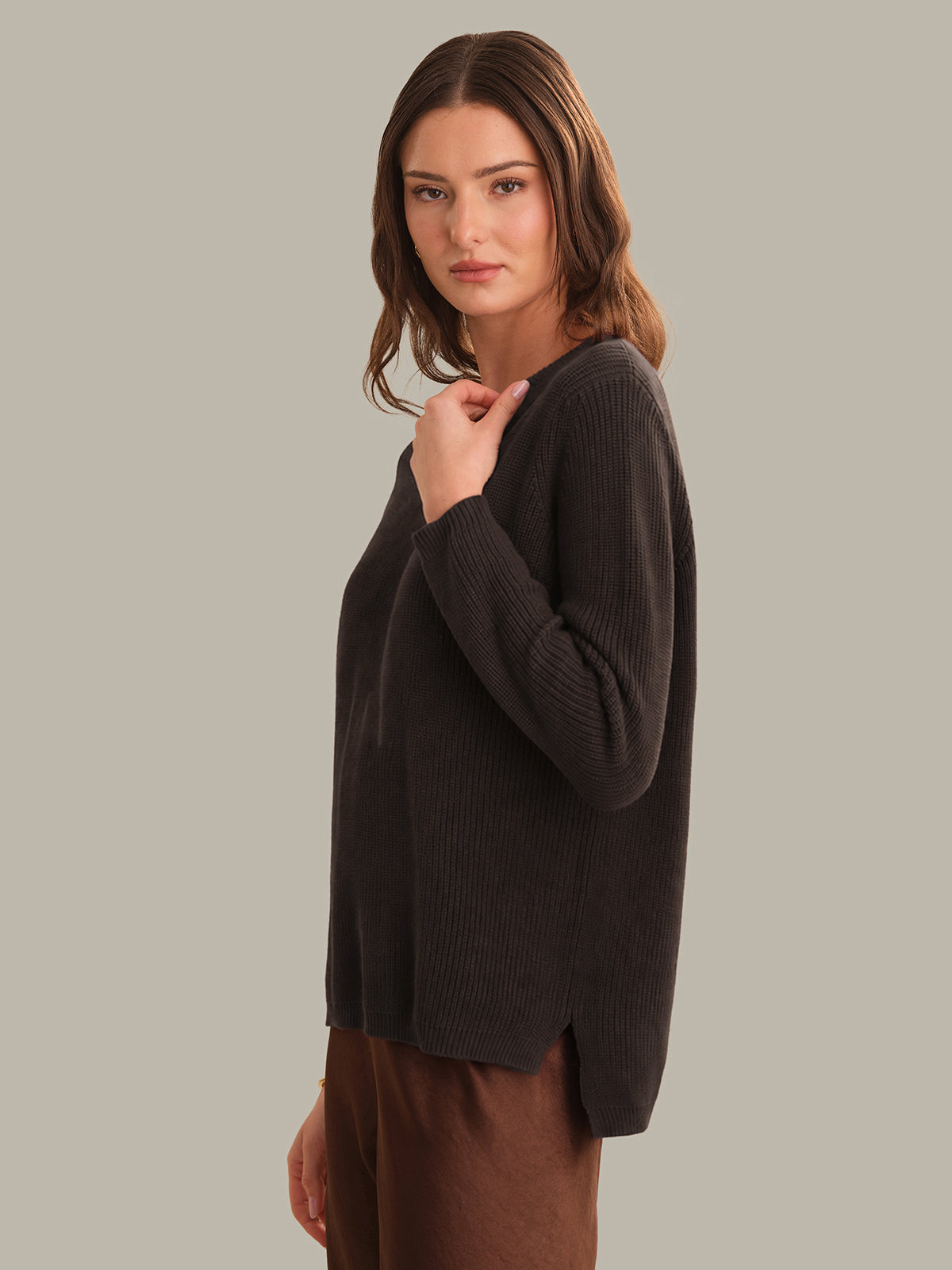 Woman wearing a dark brown sweater against a plain background