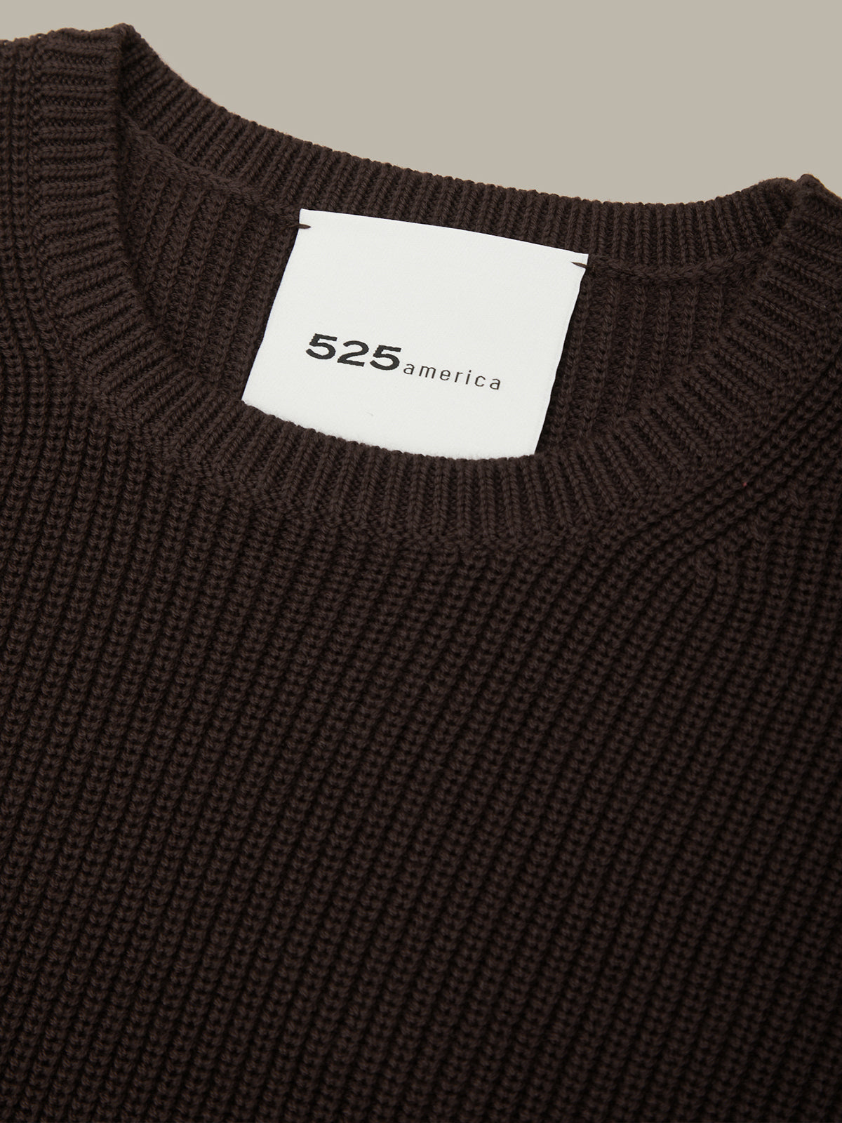 Brown sweater with a visible brand label on a neutral background