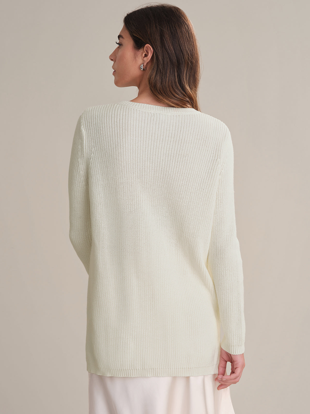 Woman wearing a white sweater against a beige background