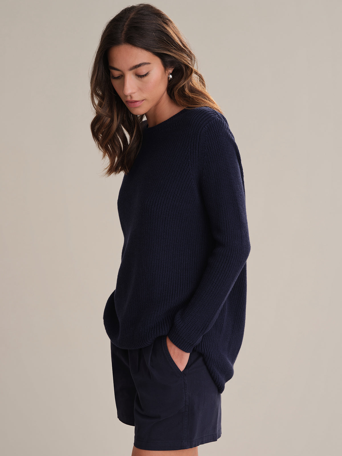 Woman wearing a navy sweater dress against a plain background