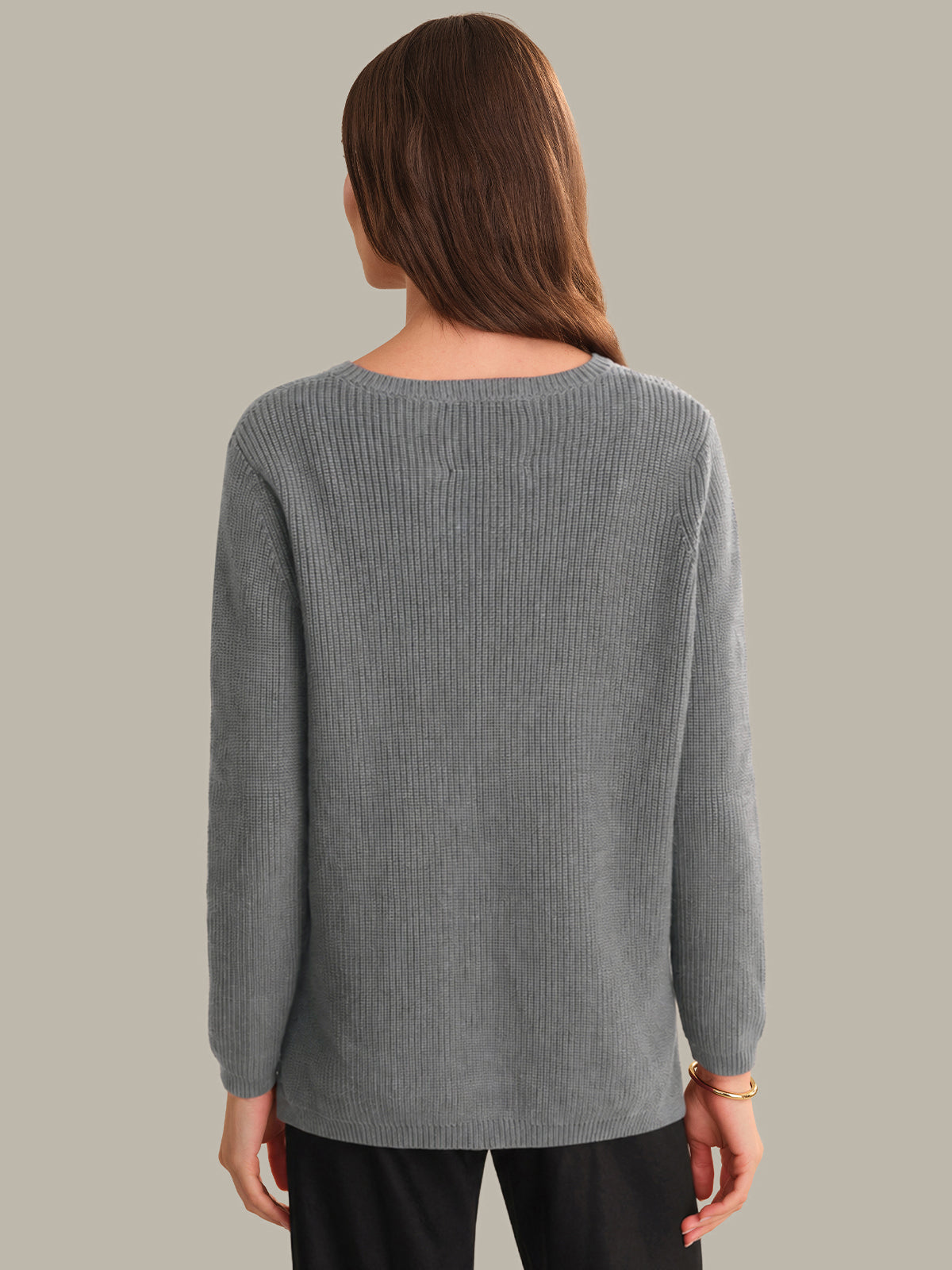 Person wearing a gray sweater against a plain background