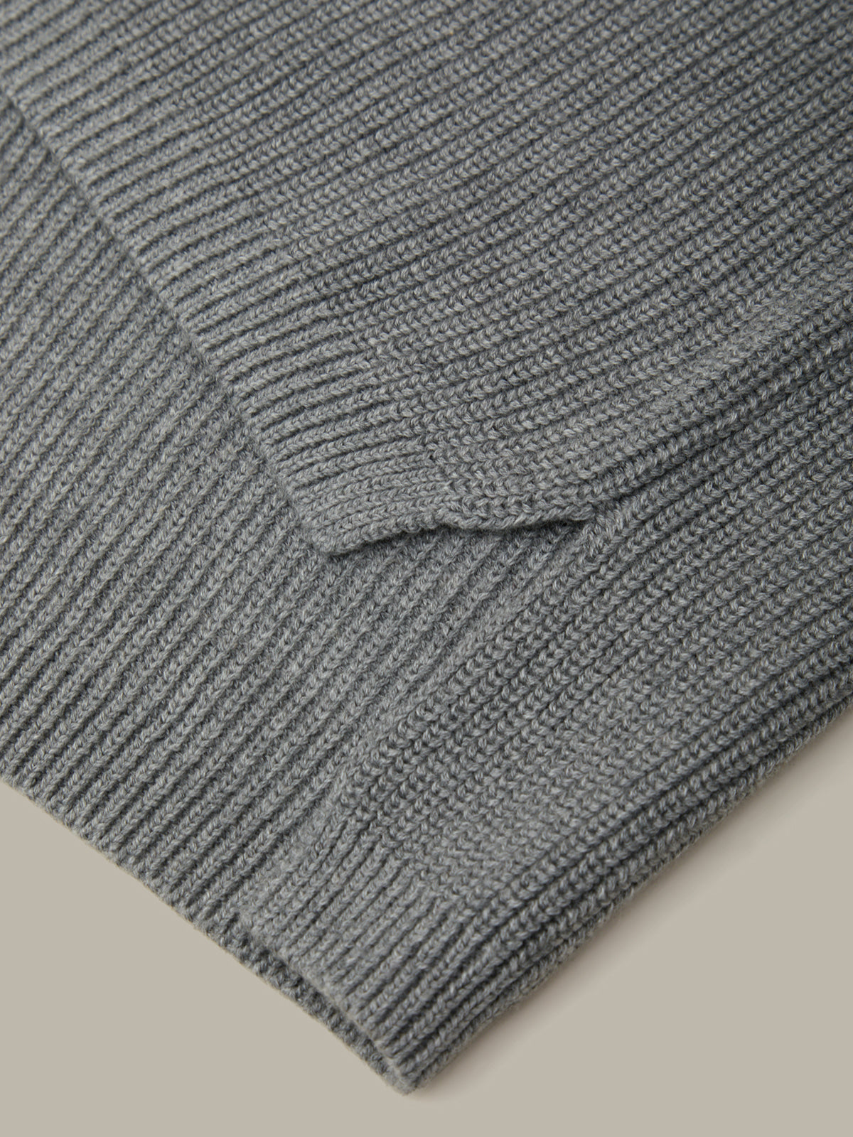 Close-up of a gray knitted sweater on a beige background