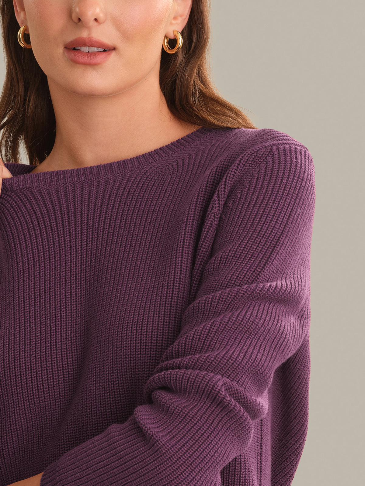 Close-up of a person wearing a purple sweater on a neutral background