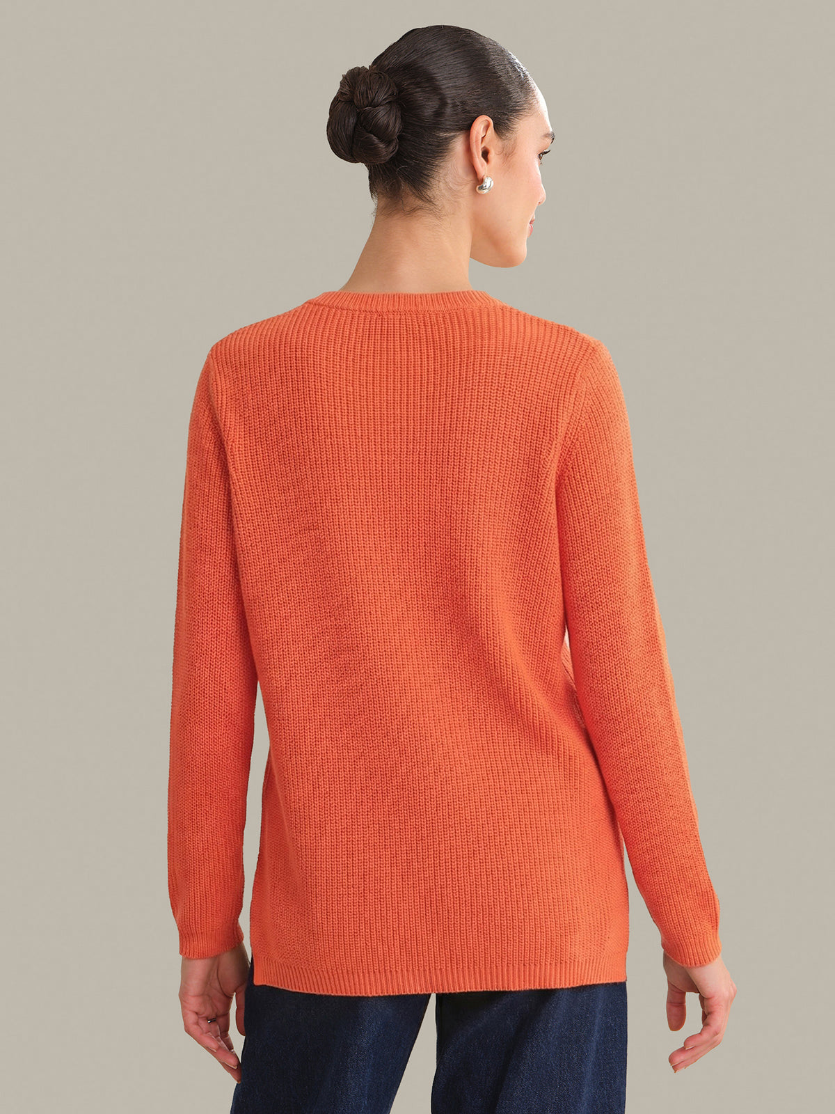 Person wearing an orange sweater against a neutral background