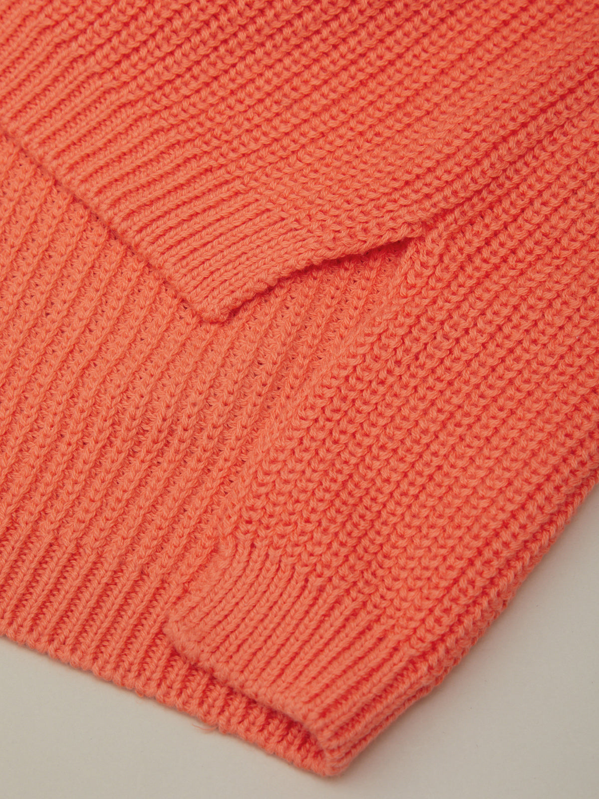 Close-up of a coral pink knitted fabric on a light gray background