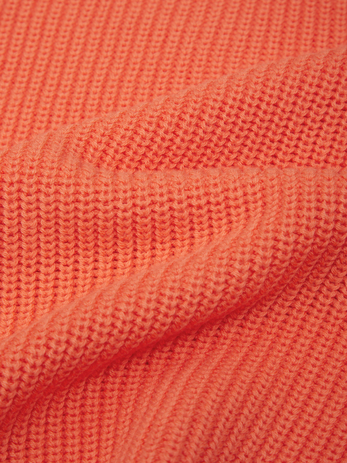 Close-up of coral-colored fabric with a textured pattern
