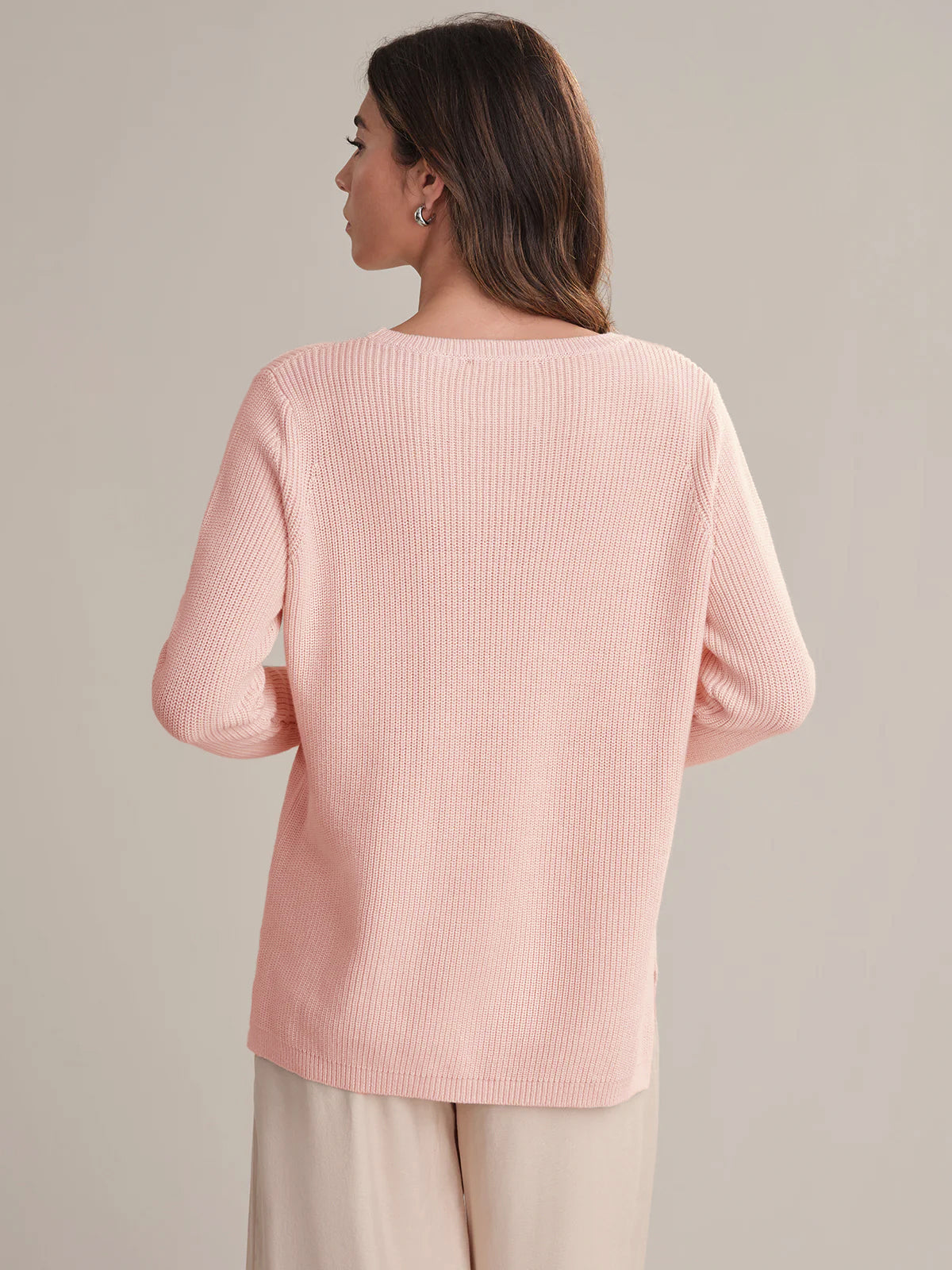 Woman wearing a light pink sweater against a neutral background