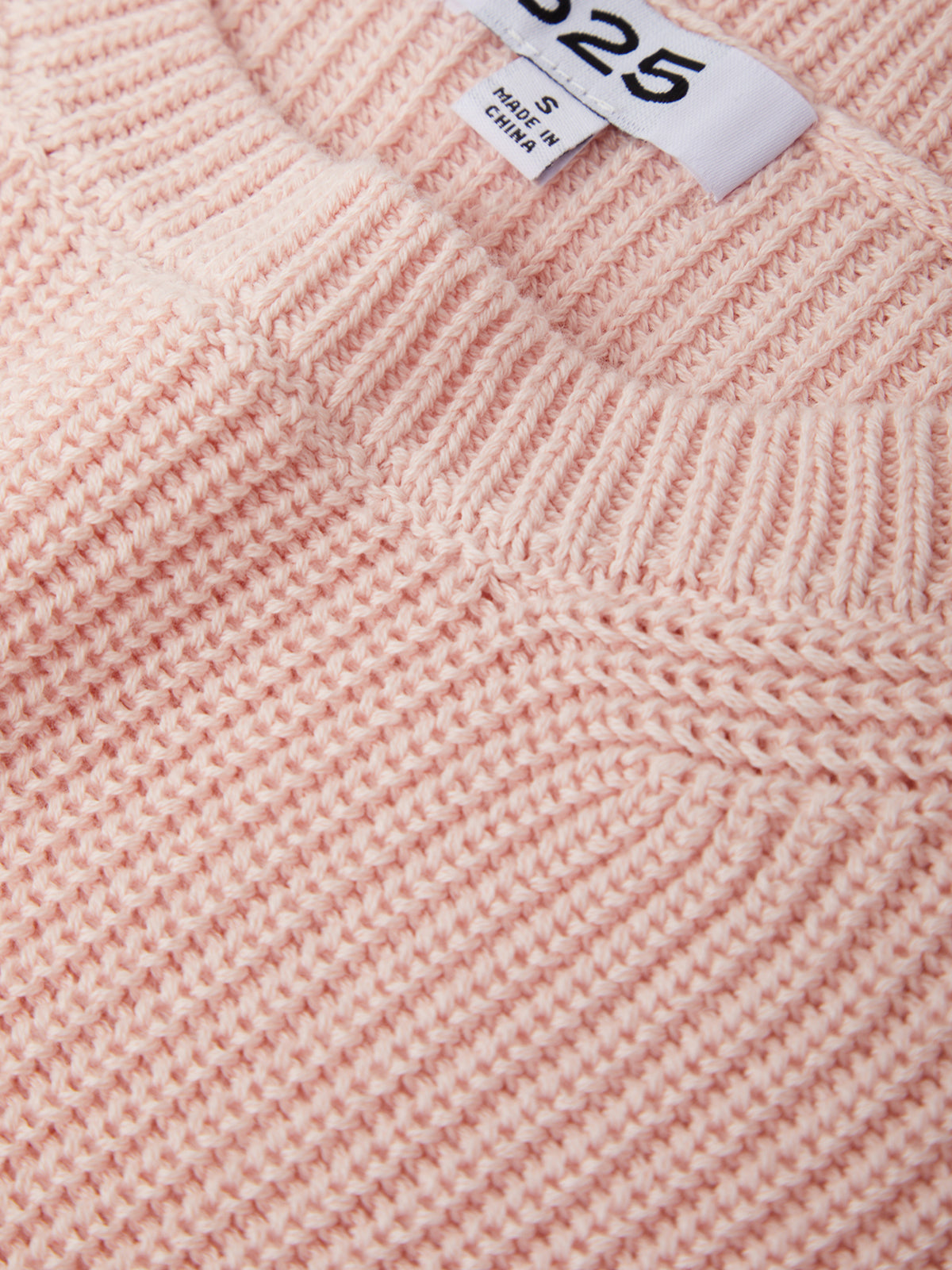Close-up of a pink knitted fabric with a label showing size '25'.