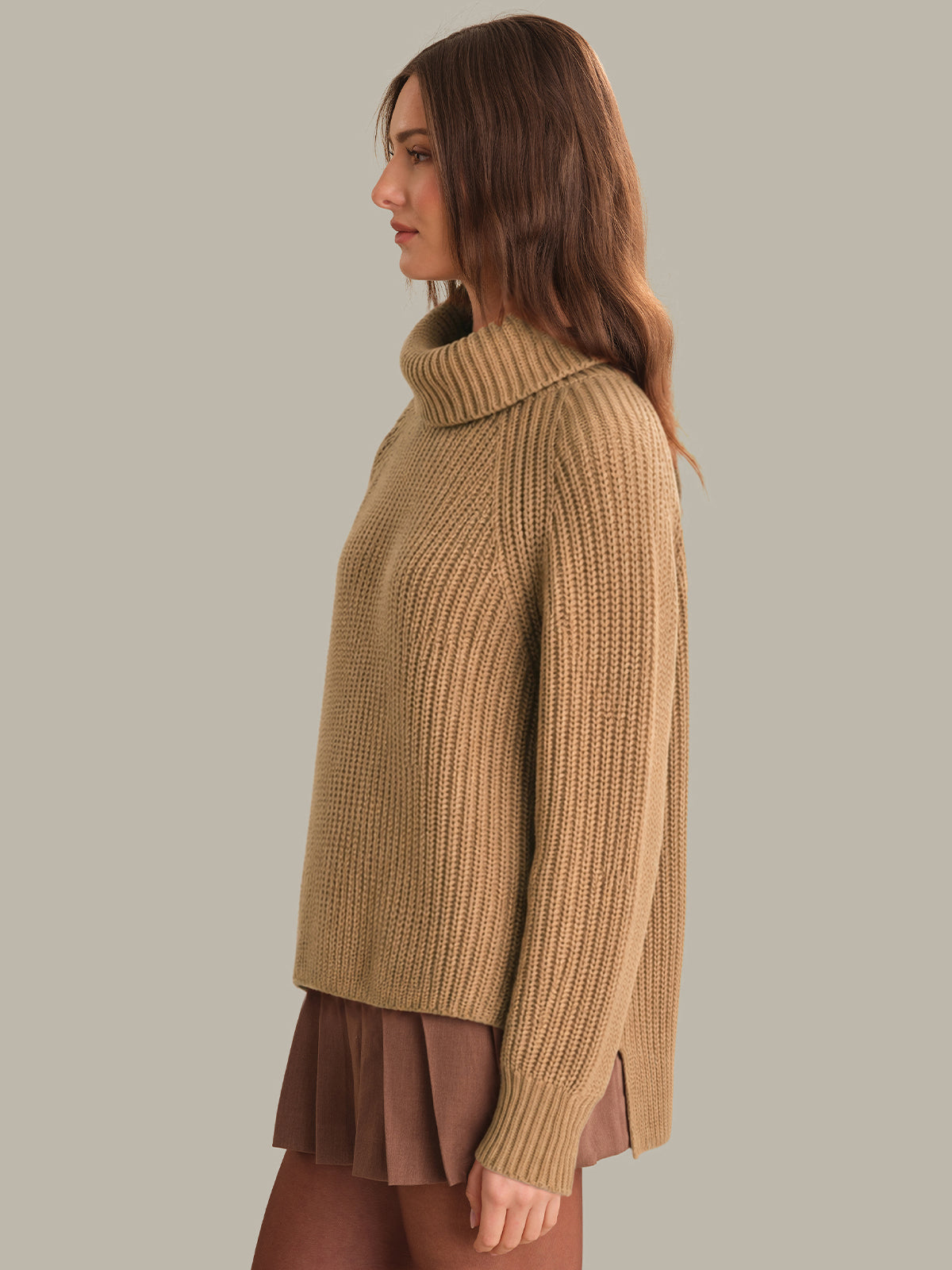 Woman wearing a beige knitted sweater and skirt on a plain background