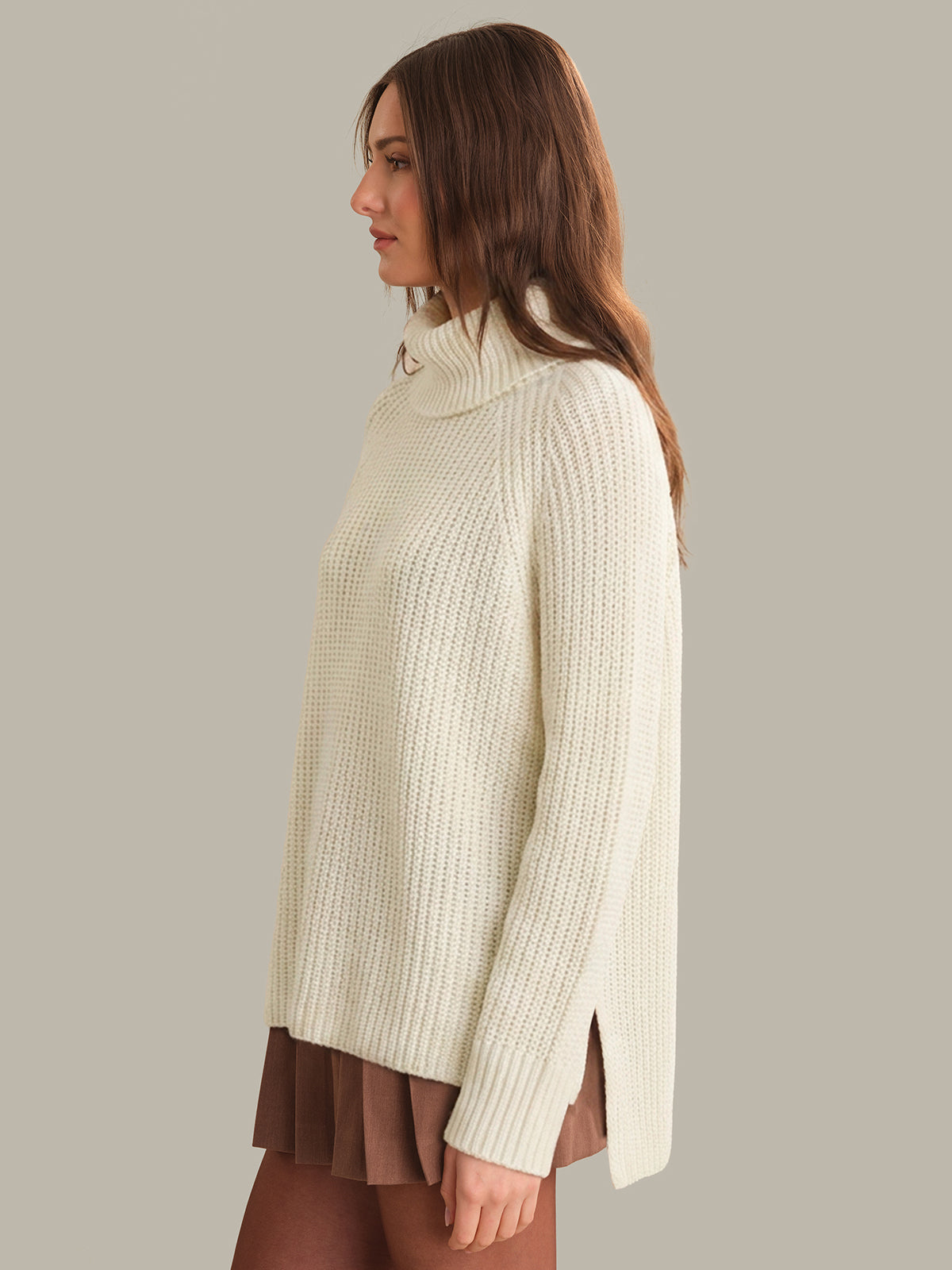 Woman wearing a cream ribbed sweater against a plain background