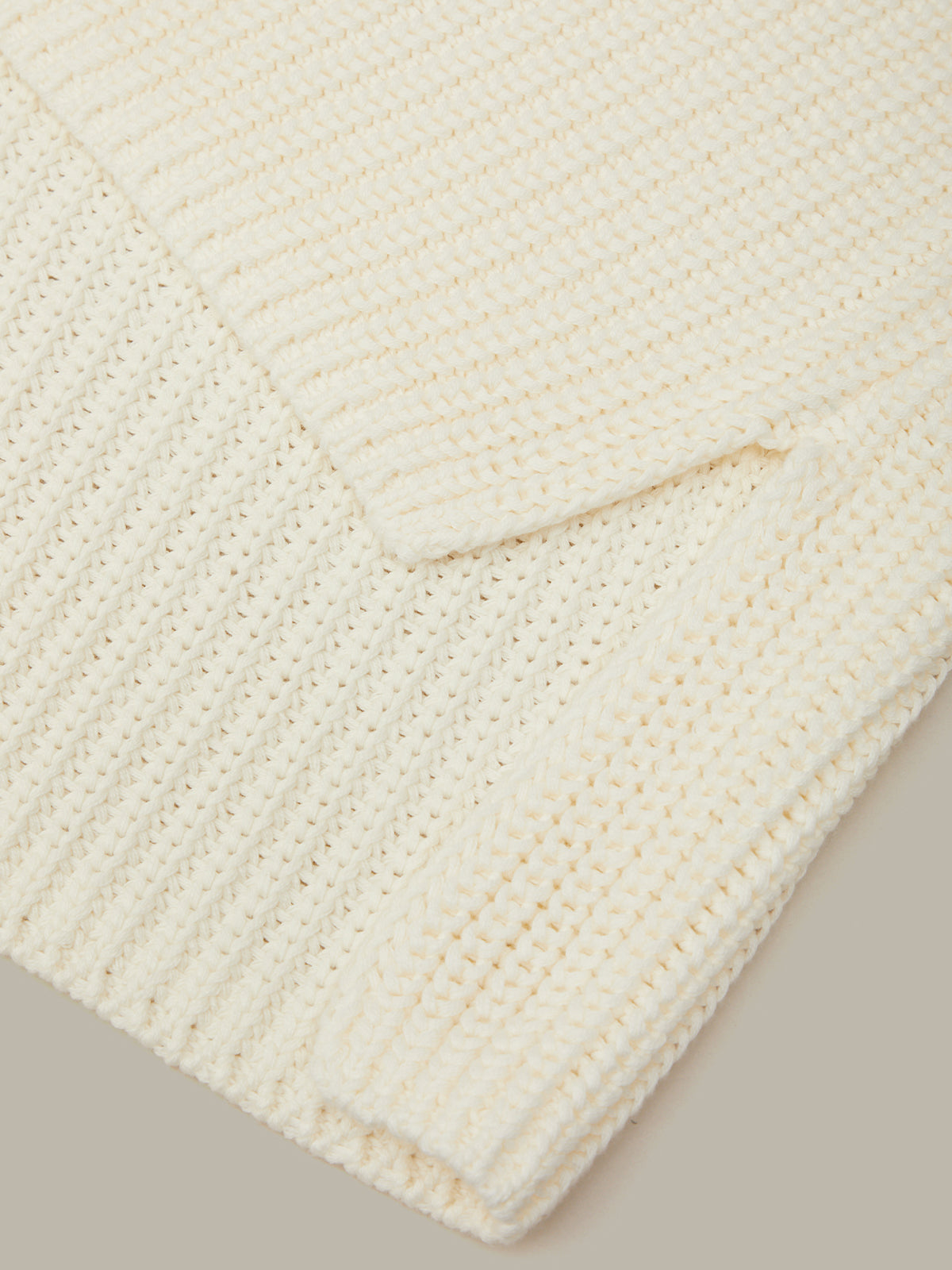 Close-up of a textured white fabric with a subtle pattern on a neutral background
