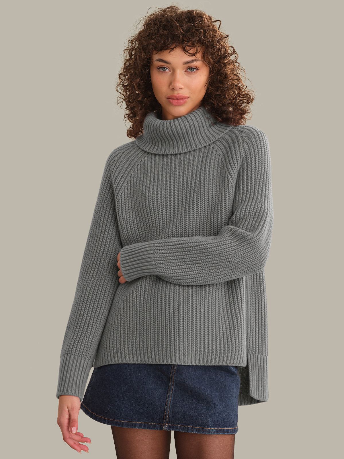 Woman wearing a gray ribbed sweater against a neutral background