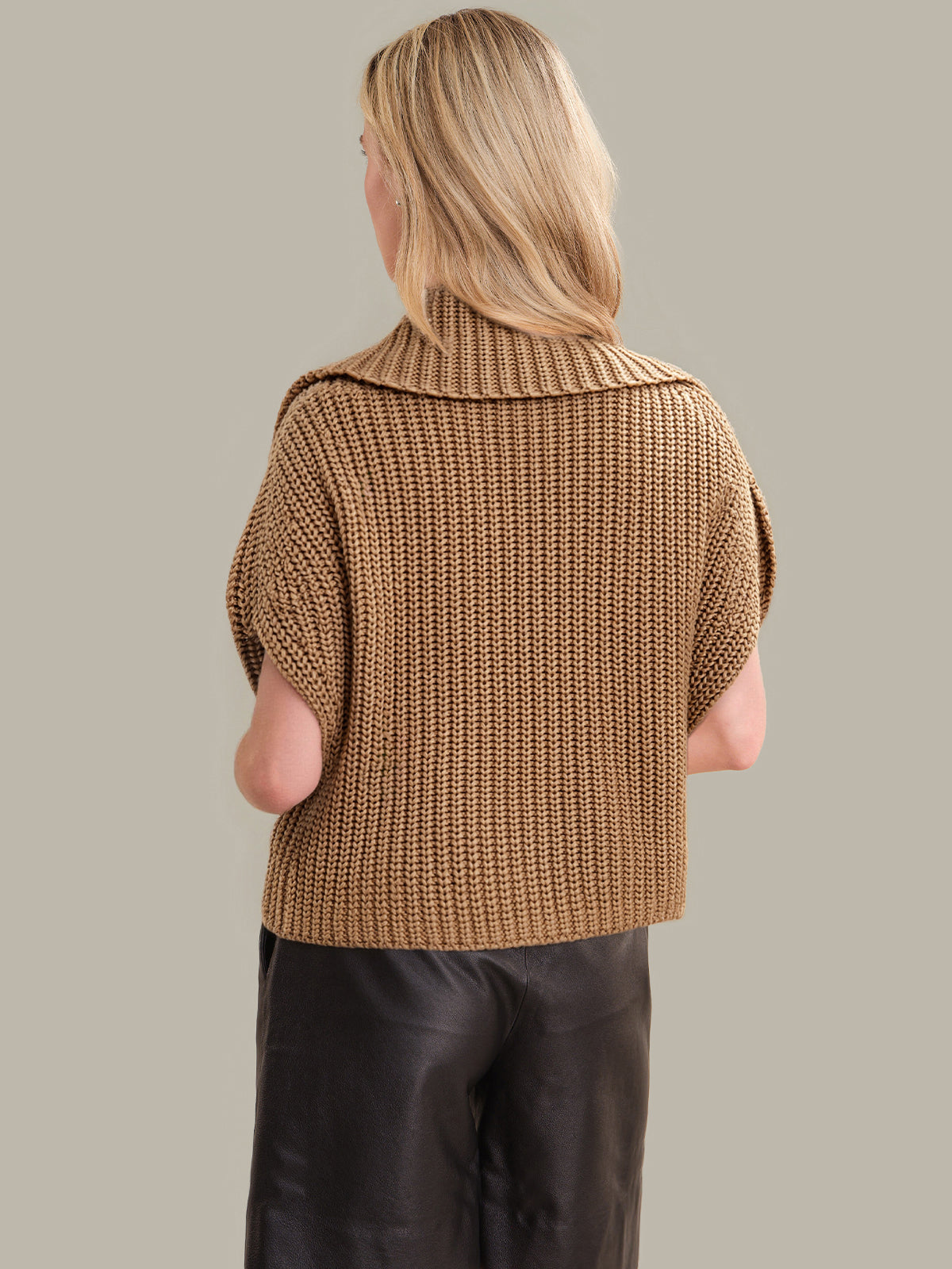 Person wearing a brown knitted vest against a neutral background