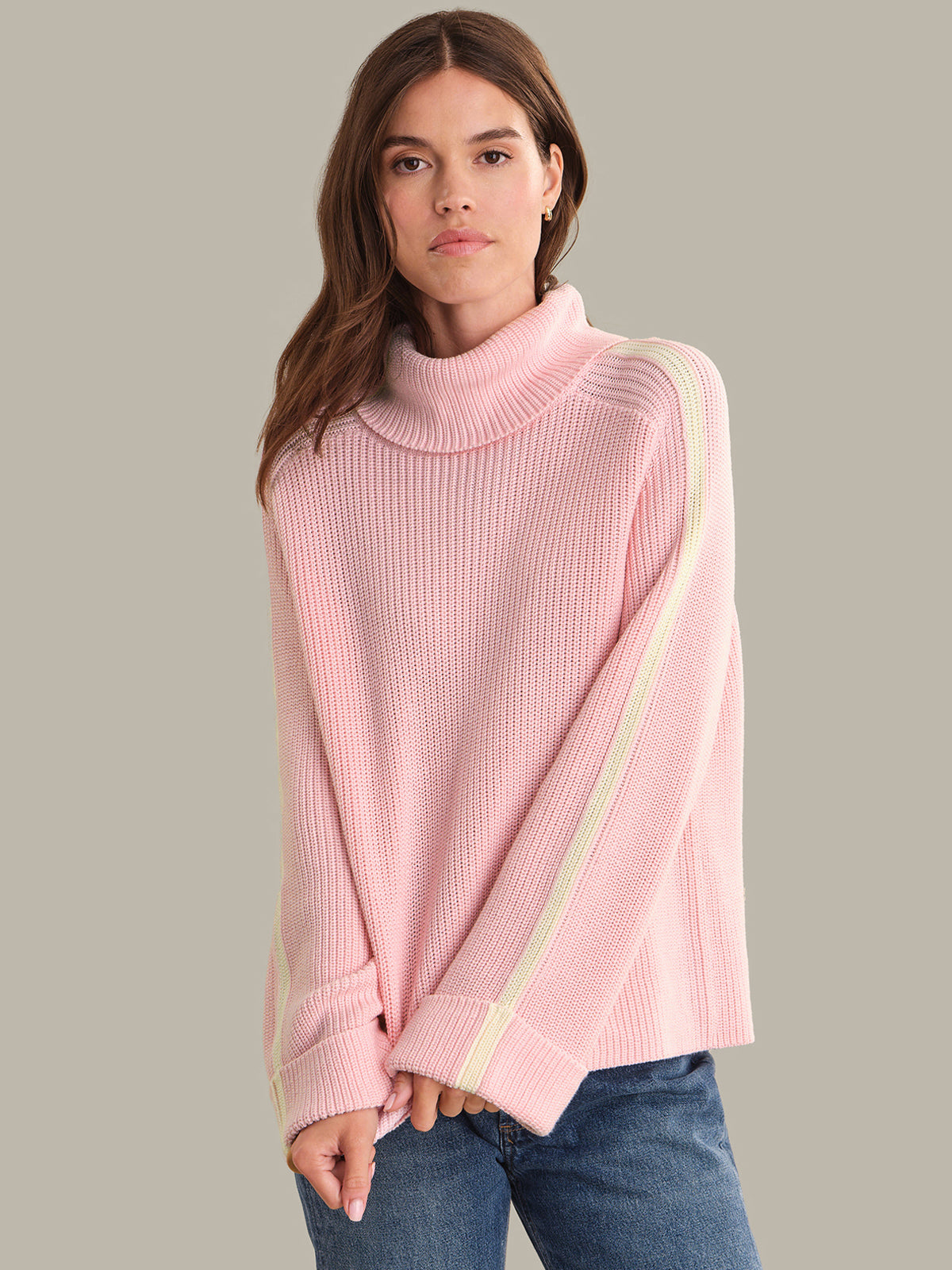 Woman wearing a pink ribbed sweater with a plain background