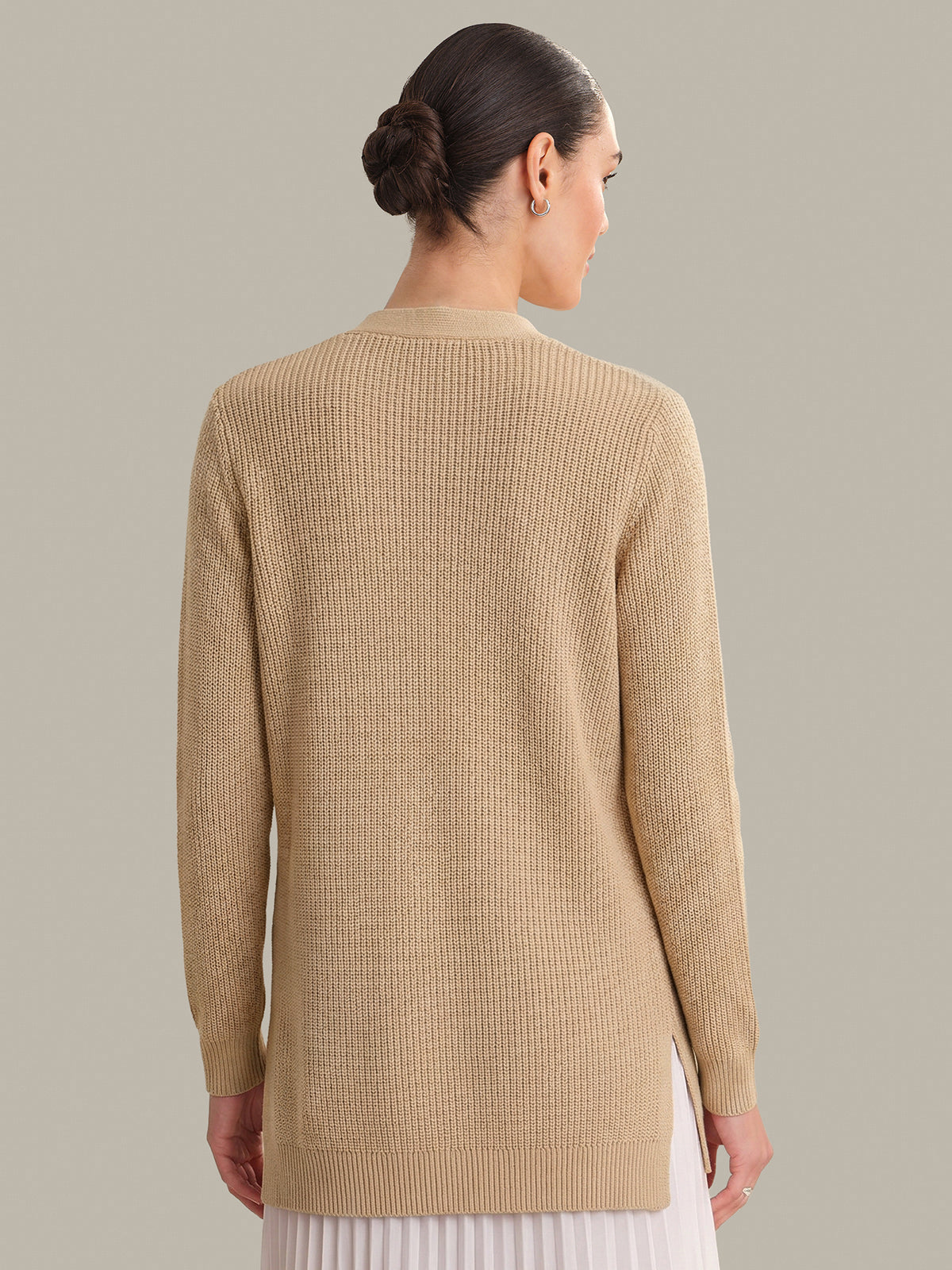 Woman wearing a beige sweater against a plain background