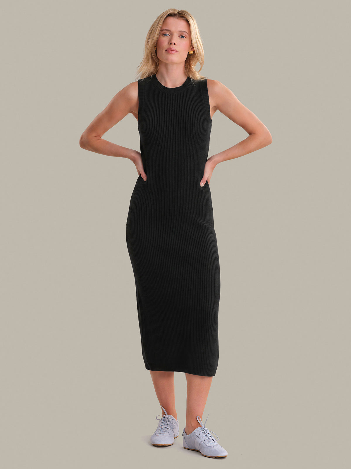 Woman wearing a black sleeveless dress against a plain background