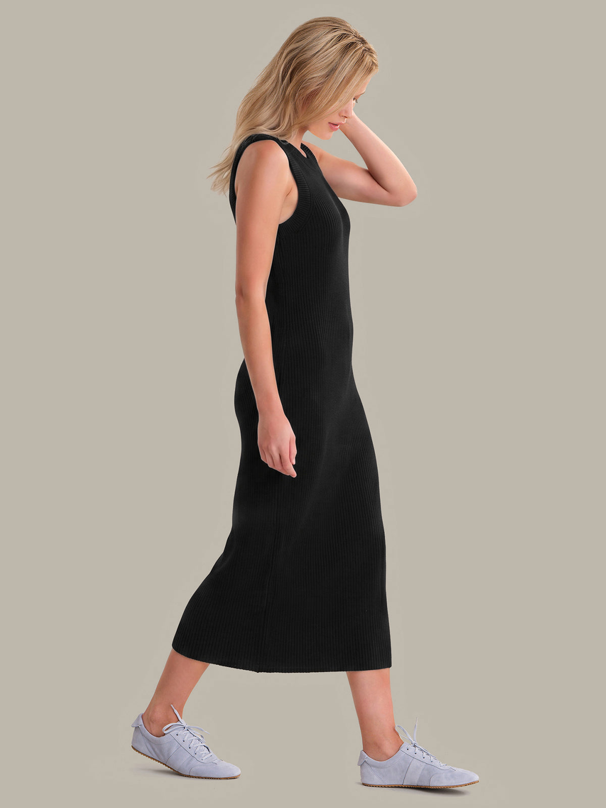 Woman wearing a black sleeveless dress against a plain background