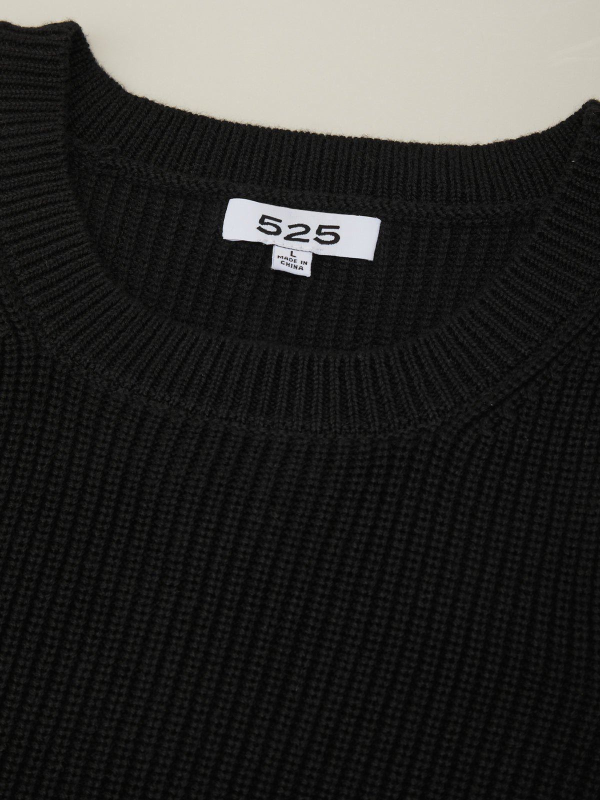 Black sweater with a visible brand label on a neutral background