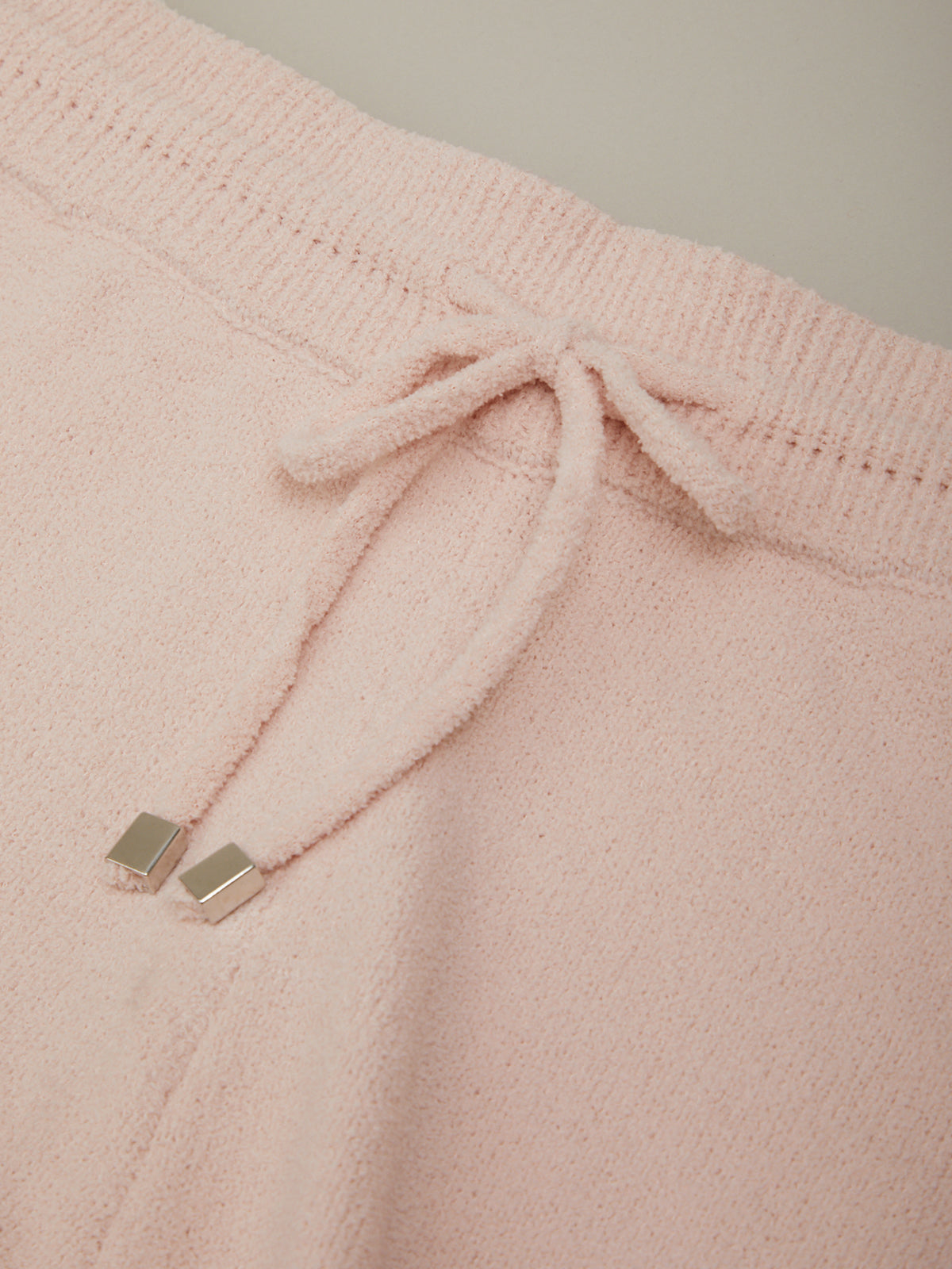 Close-up of pink drawstring pants with a plain background