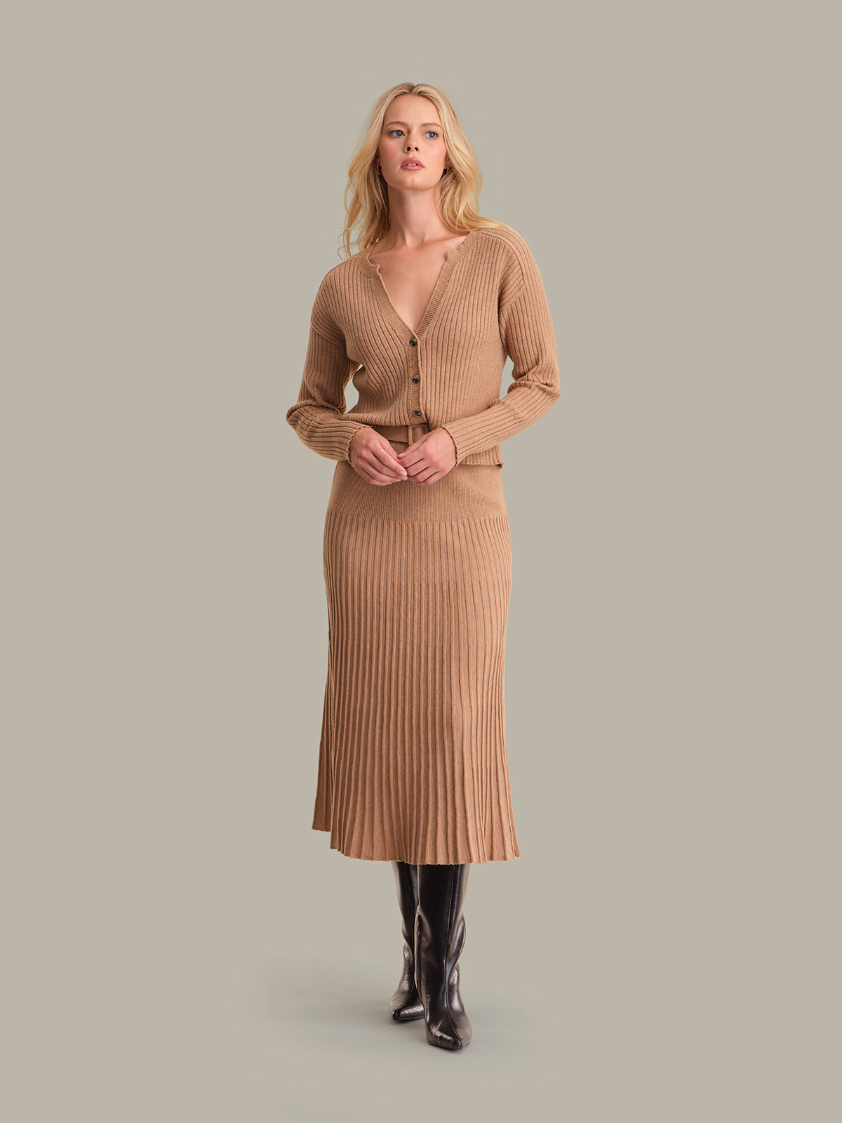 Woman wearing a brown ribbed dress with a matching cardigan on a gray background