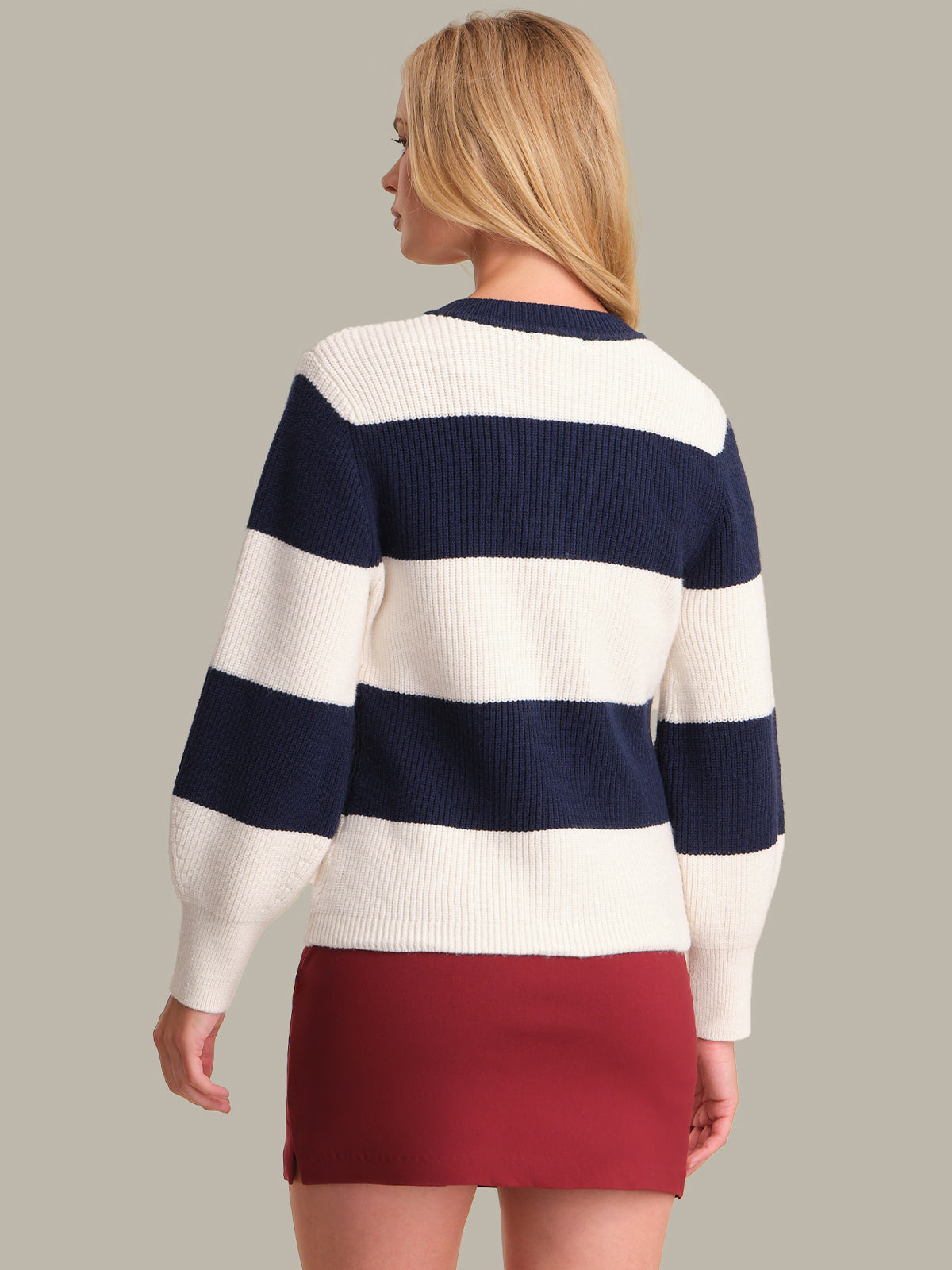 Woman wearing a navy and white striped sweater with a red skirt on a beige background
