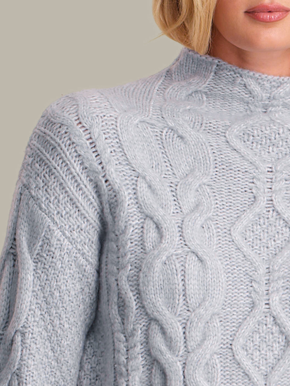 Close-up of a person wearing a textured blue sweater against a neutral background