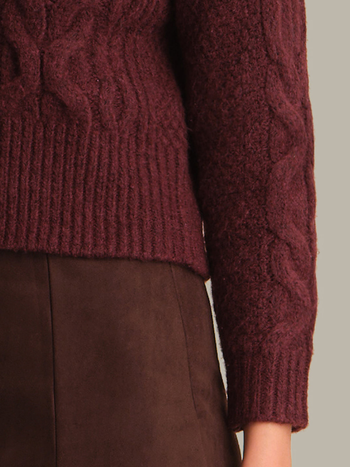 Close-up of a maroon cable knit sweater with a neutral background