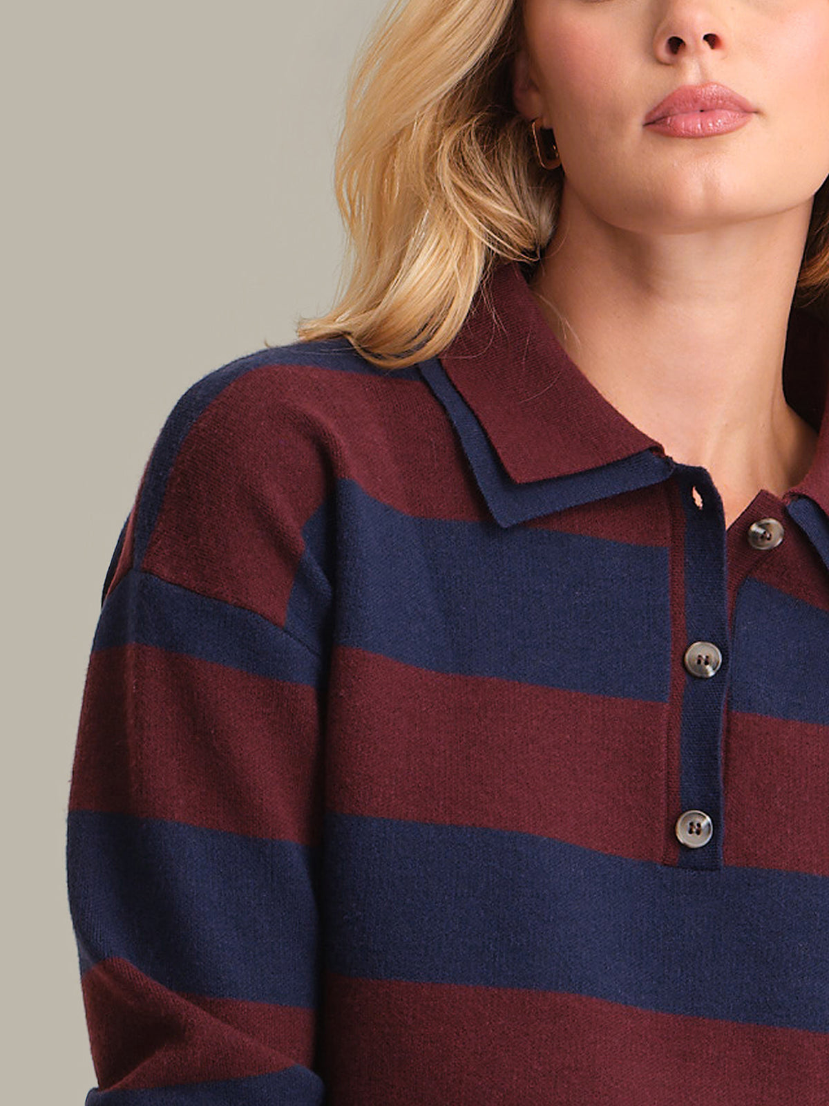 Close-up of a person wearing a maroon and navy striped shirt with a neutral background
